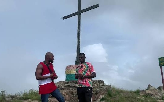 Visitors beside the iron cross at the Mount Gemi summit