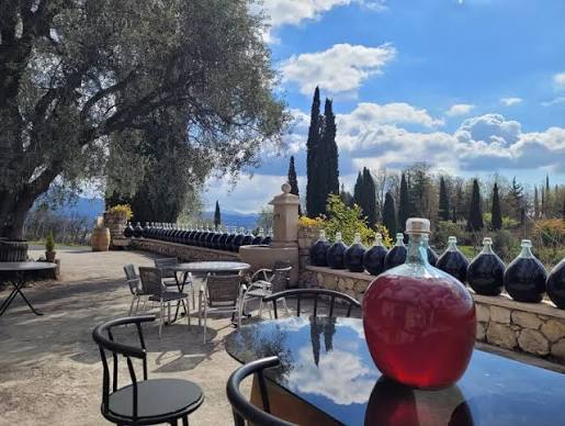 Shaded stone terrace with tables and wine demijohns
