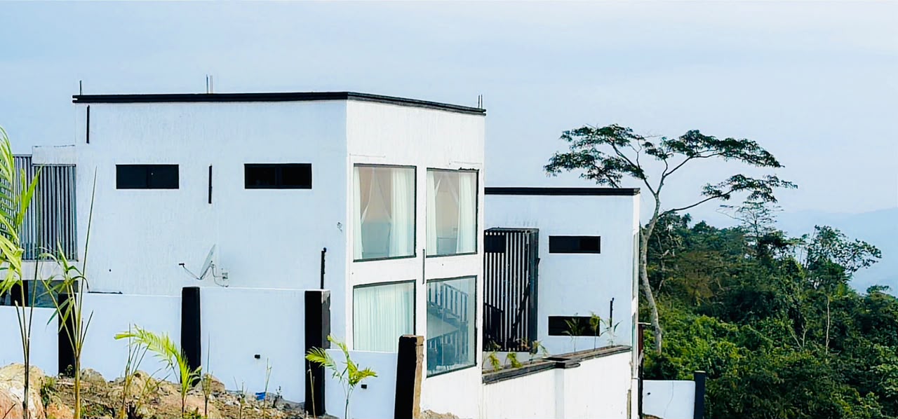 Modern white boutique hotel buildings nestled in the lush green Amedzofe mountains